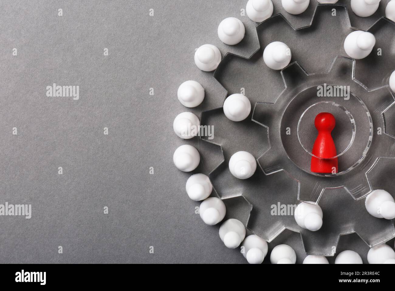 Processo di selezione dei dipendenti. Composizione piatta con ruote dentate, pedina rossa come recruiter e bianca come candidati su sfondo grigio Foto Stock