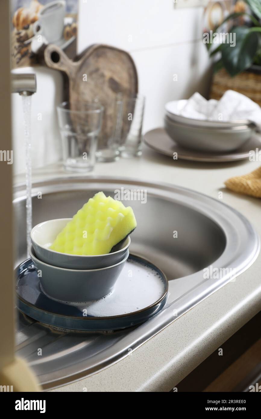 Ciotole e spugna su lavello da cucina. Piatti di lavaggio Foto stock - Alamy