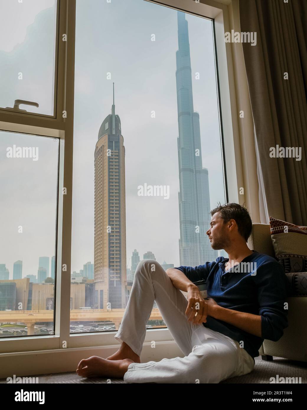 Uomini depressi seduti in una stanza di un edificio di uffici che si affaccia su Dubai Emirati Arabi Uniti Foto Stock