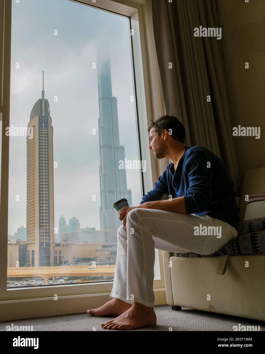 Uomini depressi seduti in una stanza di un edificio di uffici che si affaccia su Dubai Emirati Arabi Uniti Foto Stock