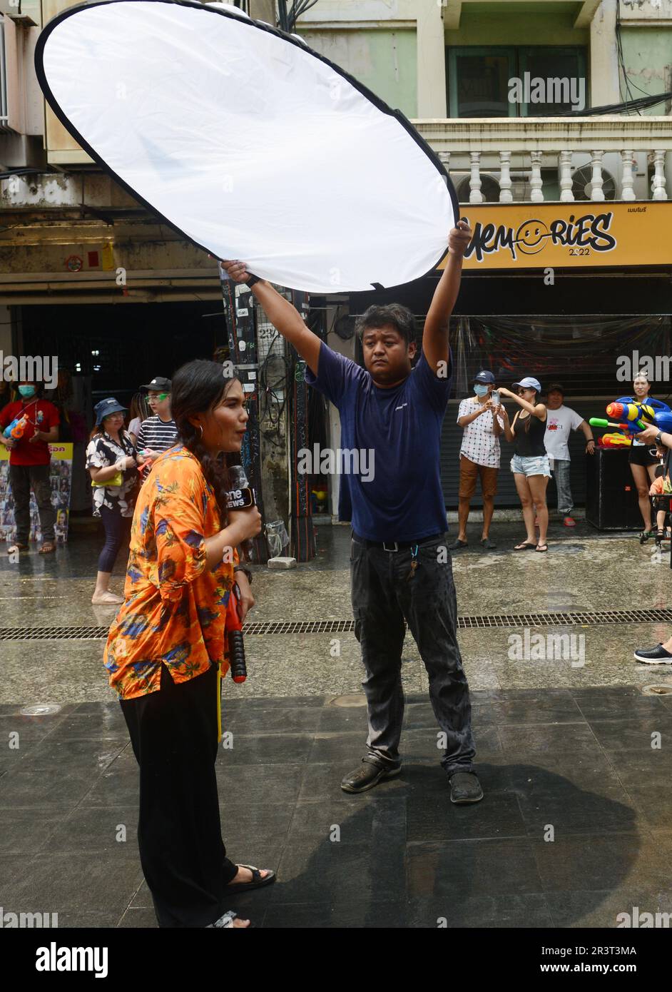 Un reporter televisivo che riferisce sulla celebrazione del festival di Songkran a Khaosan Road, Bangkok, Thailandia. Foto Stock