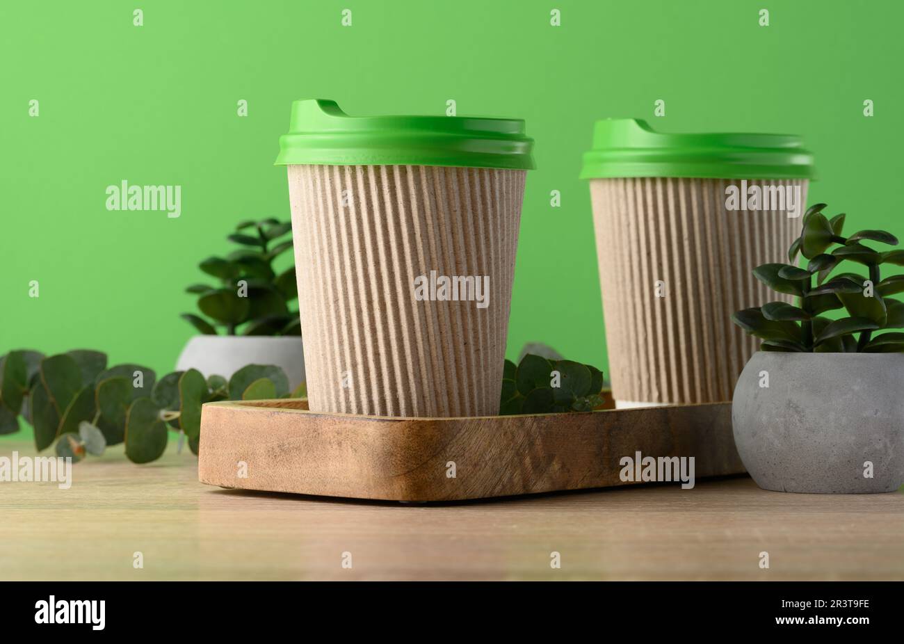 Tazze di carta marrone con coperchio verde in plastica per caffè e tè su sfondo verde Foto Stock