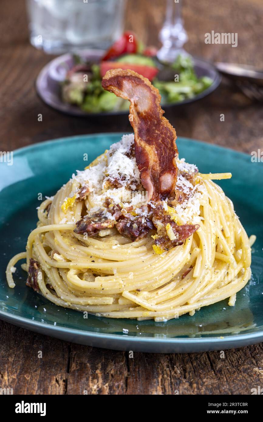Spaghetti alla carbonara con insalata su legno Foto Stock