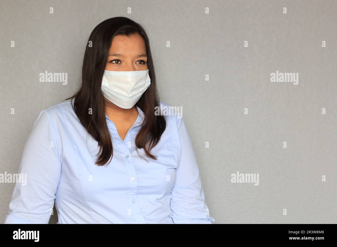 Donna latina con blusa blu e maschera di protezione uso clinico per pandemia covida Foto Stock