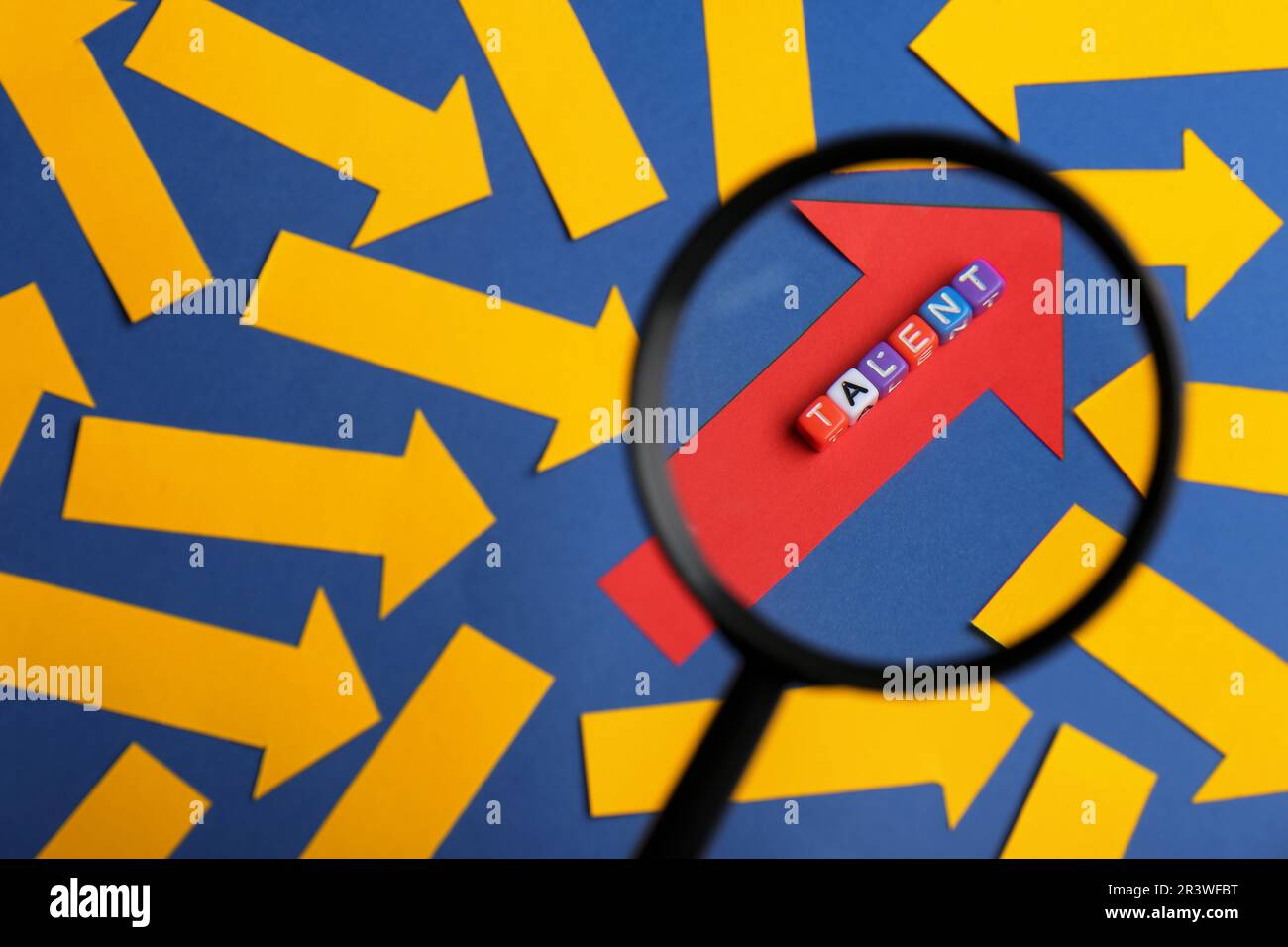 Processo di reclutamento, ricerca dipendente. Guarda attraverso la lente d'ingrandimento della freccia di carta rossa e la parola Talent fatta di cubi colorati tra quelli gialli Foto Stock