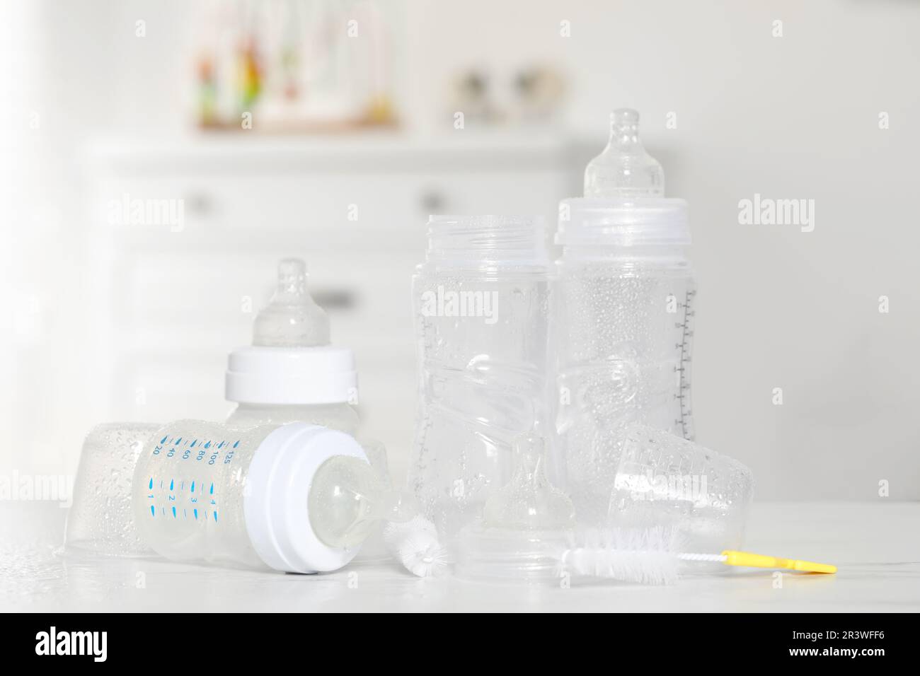 Pulire i biberon con le tettarelle dopo la sterilizzazione e la spazzola  per la pulizia sul tavolo bianco all'interno Foto stock - Alamy