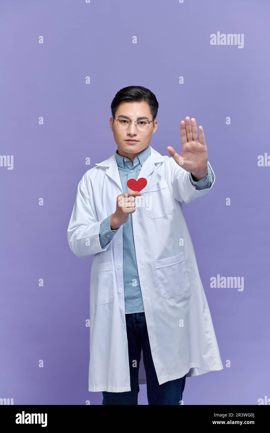 Giovane uomo asiatico medico tenendo il cuore rosso mentre guardando stressato Foto Stock