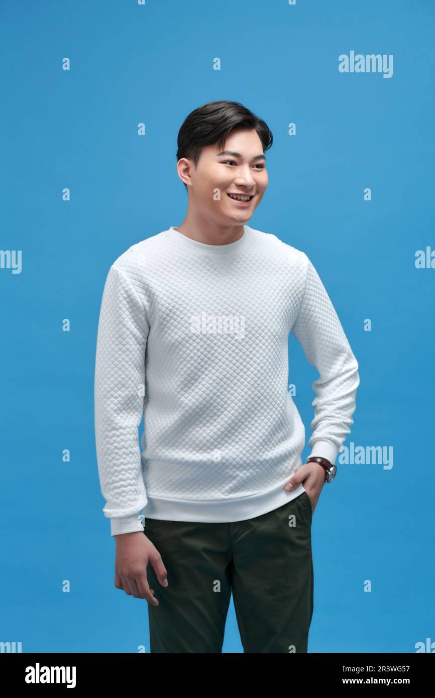 Elegante e attraente giovane uomo sorridente che indossa una t-shirt bianca in posa in studio Foto Stock
