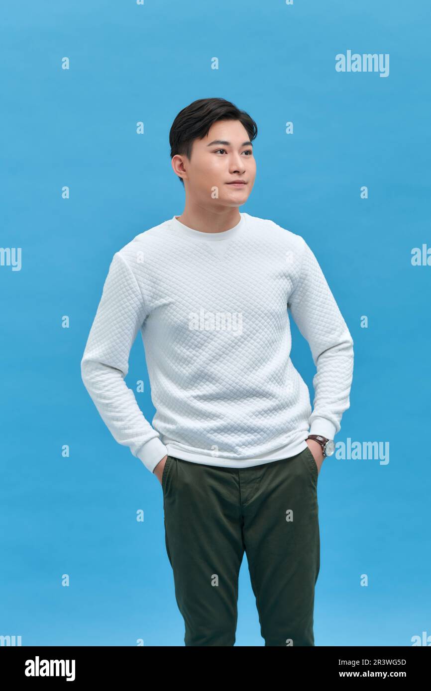 Ritratto di un giovane sorridente bell'uomo asiatico in piedi con le mani in tasca isolato Foto Stock