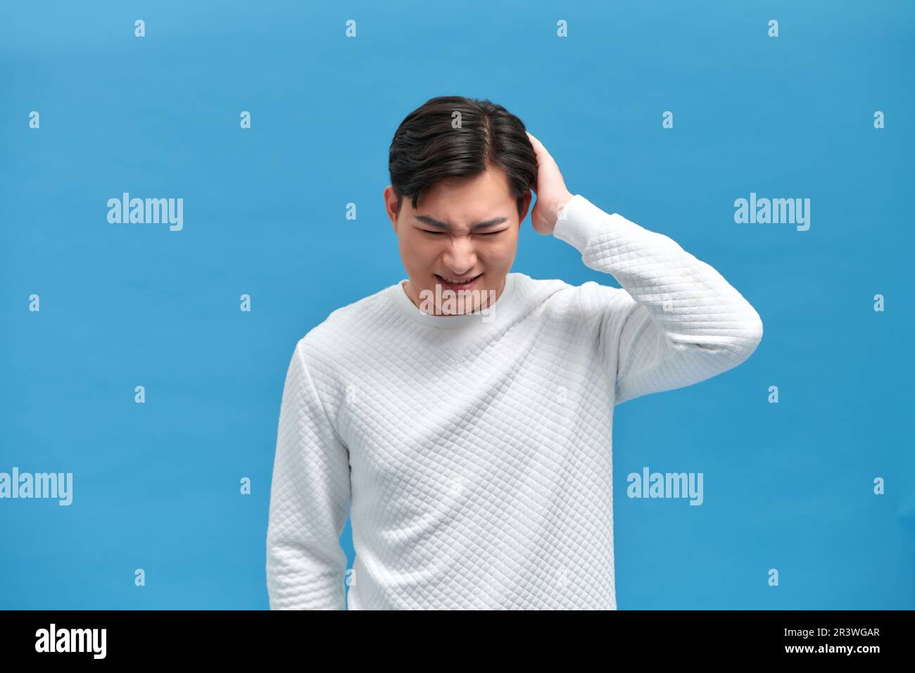 Giovane uomo asiatico bello con mano sulla testa per il dolore in testa perché stress. Emicrania sofferente Foto Stock