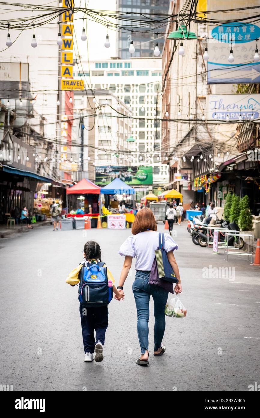 Una madre prende sua figlia dalla scuola e cammina lungo la vuota Soi 1 che è la strada principale di Patpong, la famosa zona a luci rosse di Bangkok. Foto Stock