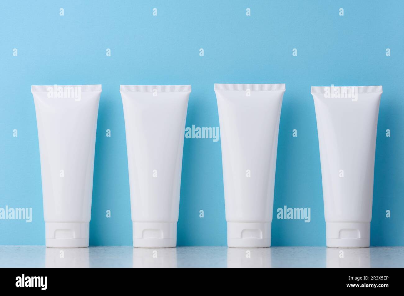 Tubi in plastica bianca per prodotti cosmetici su sfondo blu, pubblicità e branding dei prodotti Foto Stock