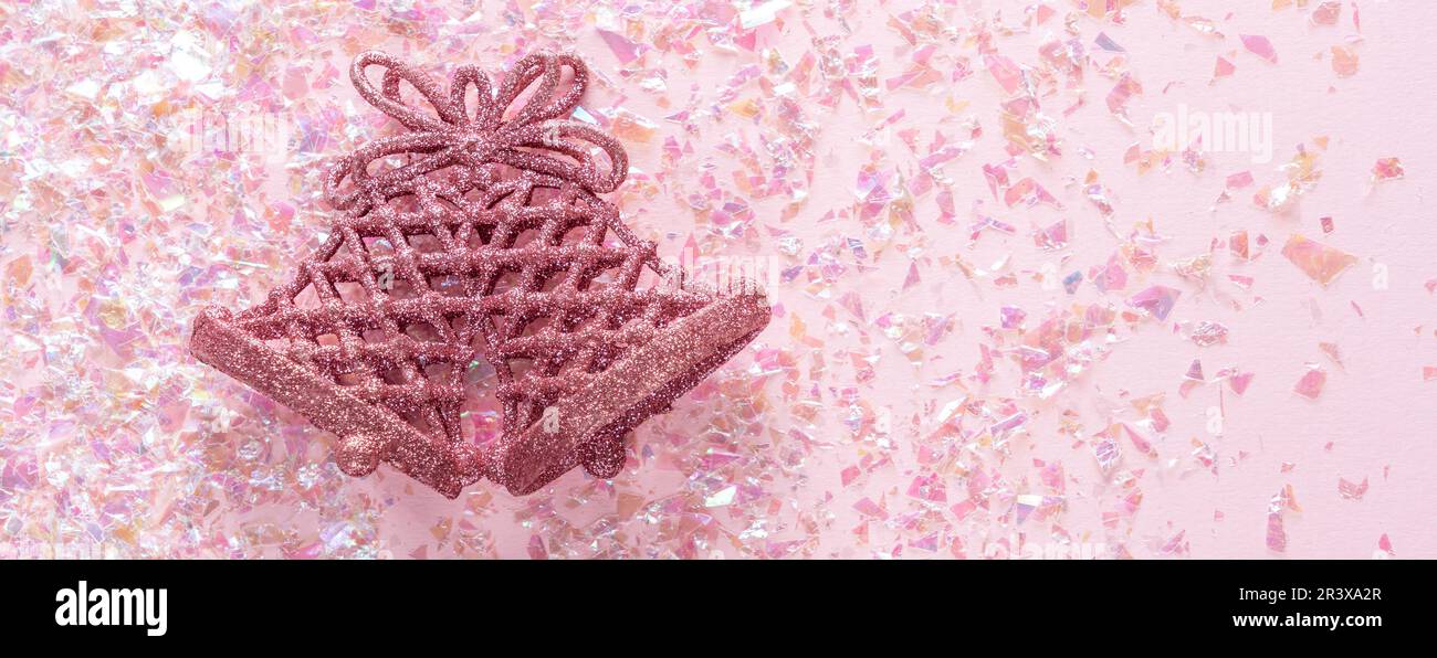 Campana Jingle vintage su sfondo rosa glitter. Concetto di Natale minimo. Felice Anno Nuovo. Disposizione piatta, vista dall'alto, spazio per la copia Foto Stock
