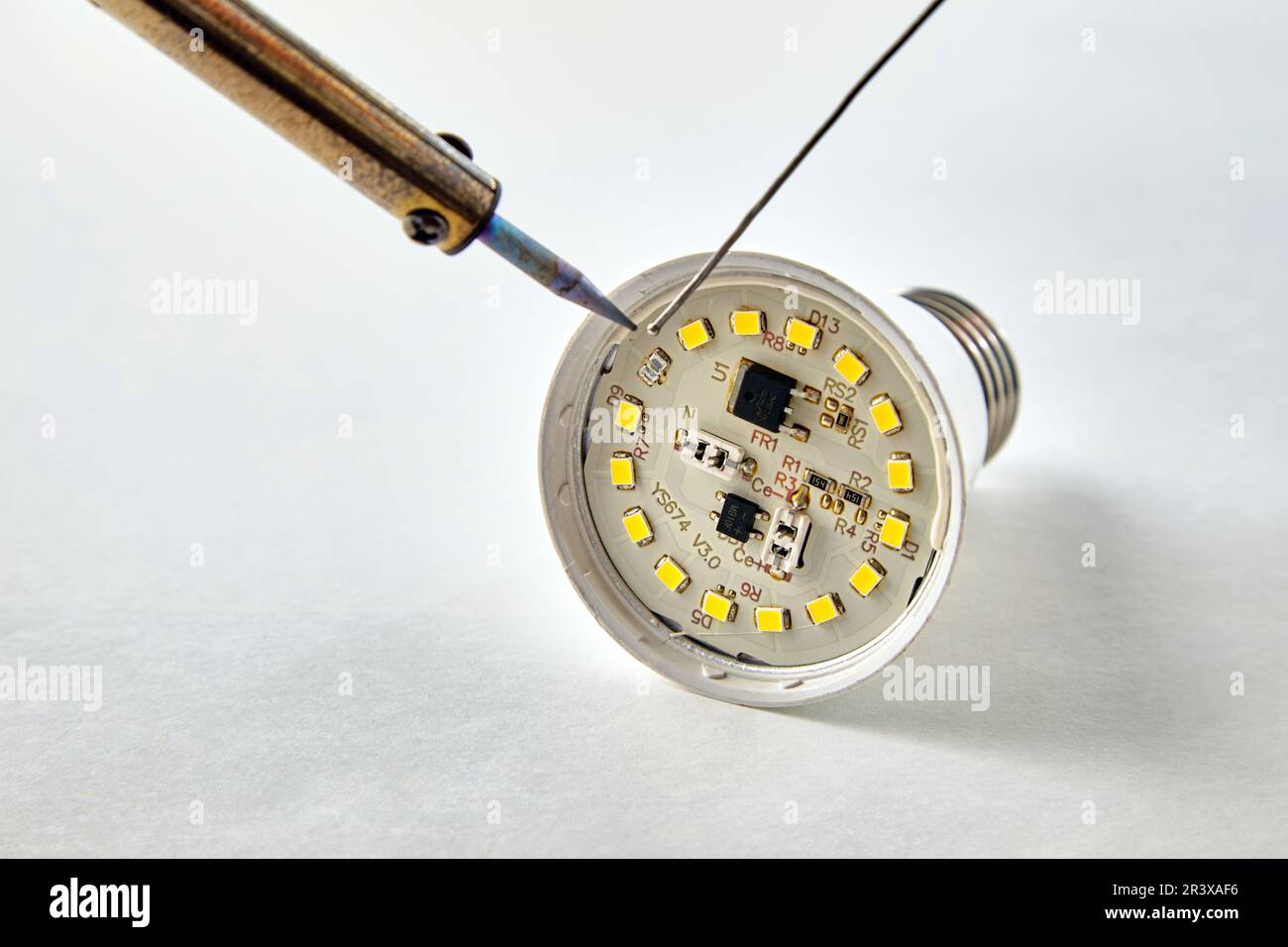 Saldatura di un LED bruciato in una lampadina LED su sfondo bianco Foto Stock