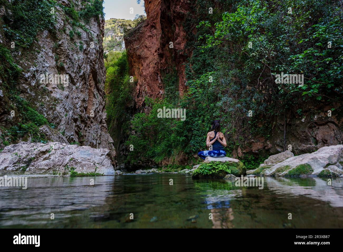 Donna che pratica yoga sul fiume, ponte di Dio, Akchour, Parco Naturale Talassettane, regione di Rif, marocco, africa. Foto Stock