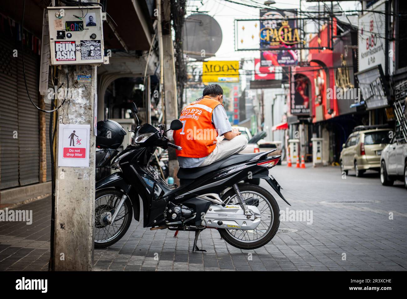 Un motociclista thailandese che lavora come servizio taxi prende una pausa seduto in bicicletta su Walking Street Pattaya Thailandia. Foto Stock