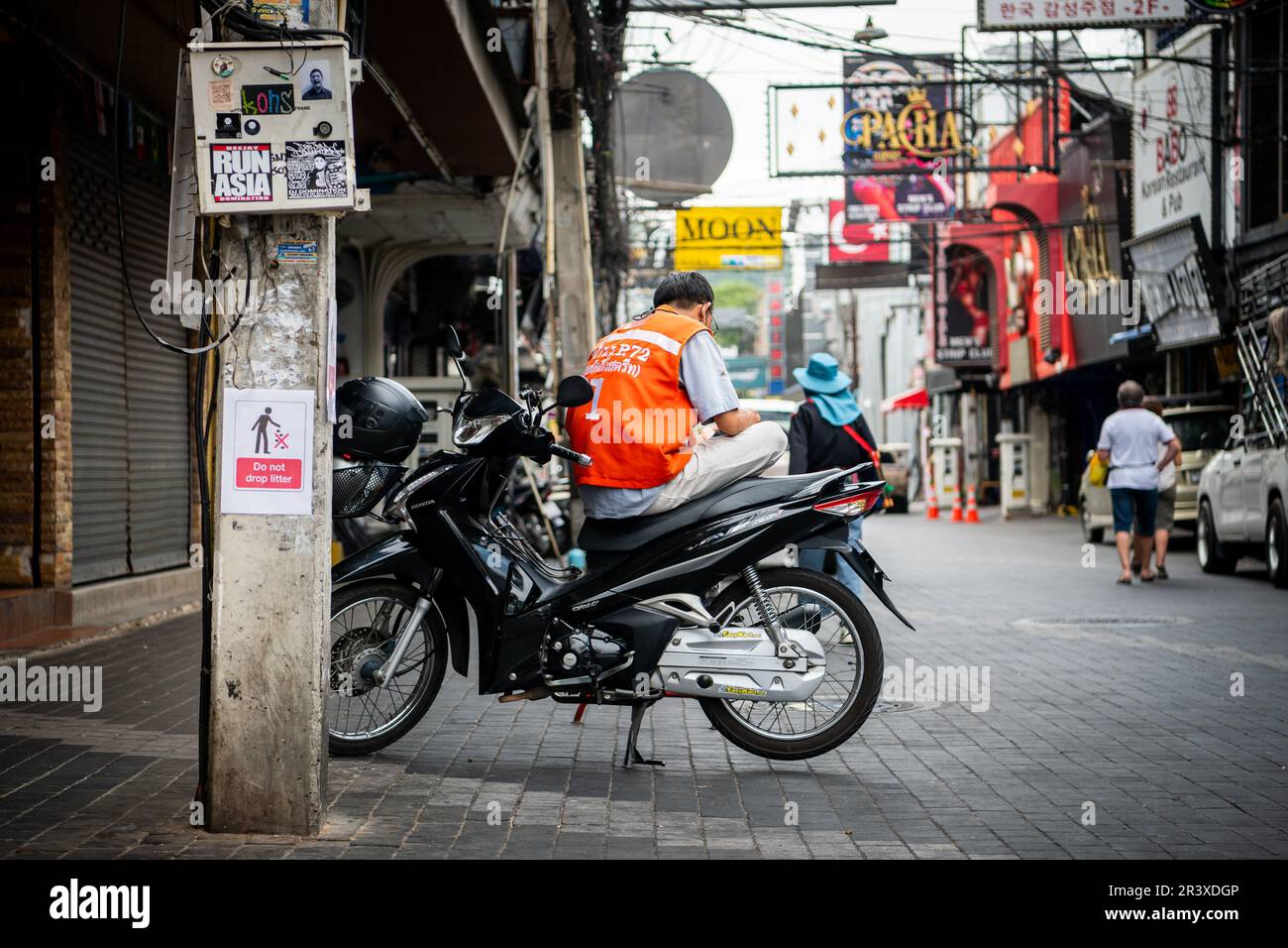 Un motociclista thailandese che lavora come servizio taxi prende una pausa seduto in bicicletta su Walking Street Pattaya Thailandia. Foto Stock