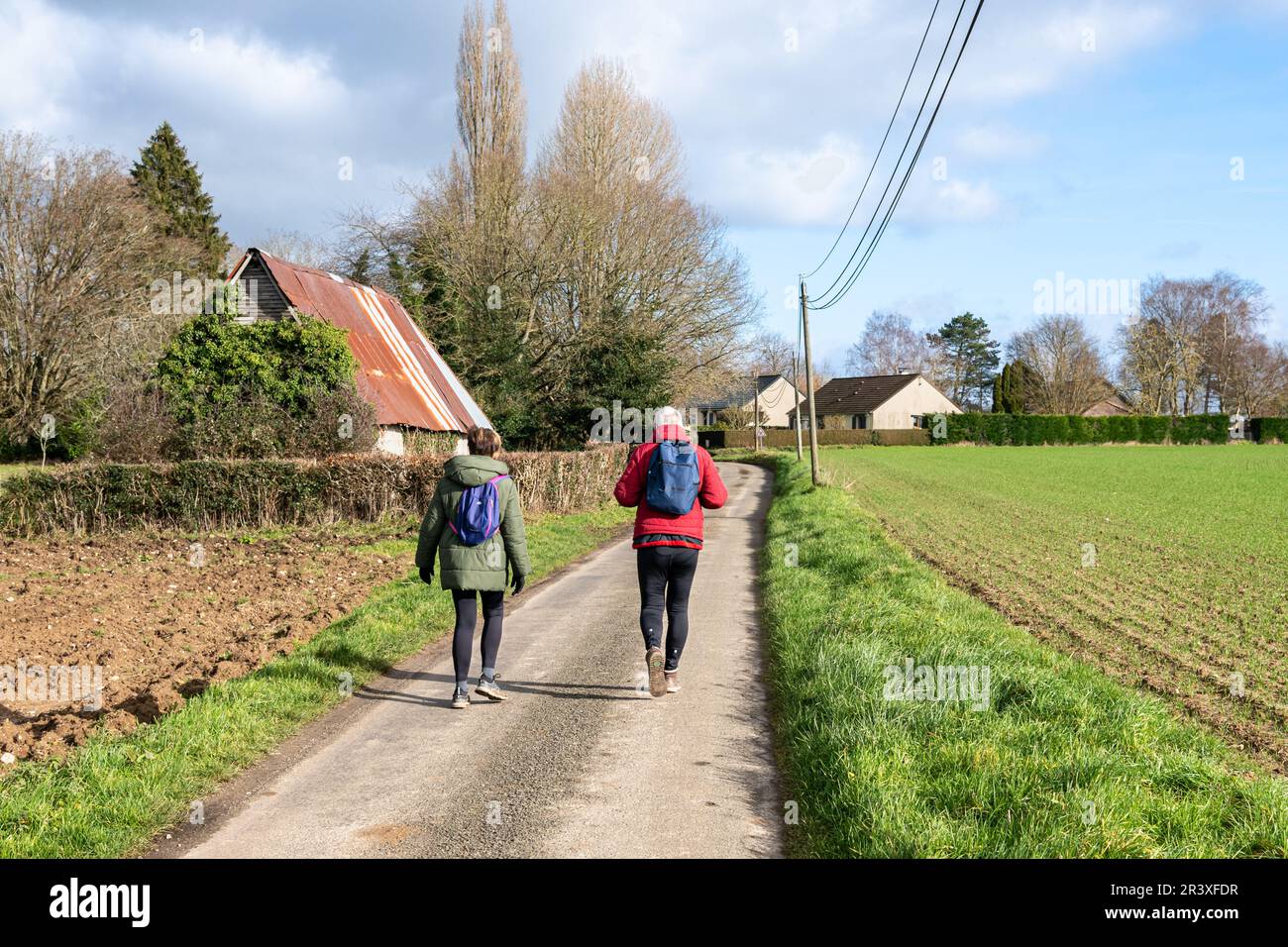 Coppia di pensionati che camminano su una strada di campagna in una giornata di sole in inverno Foto Stock