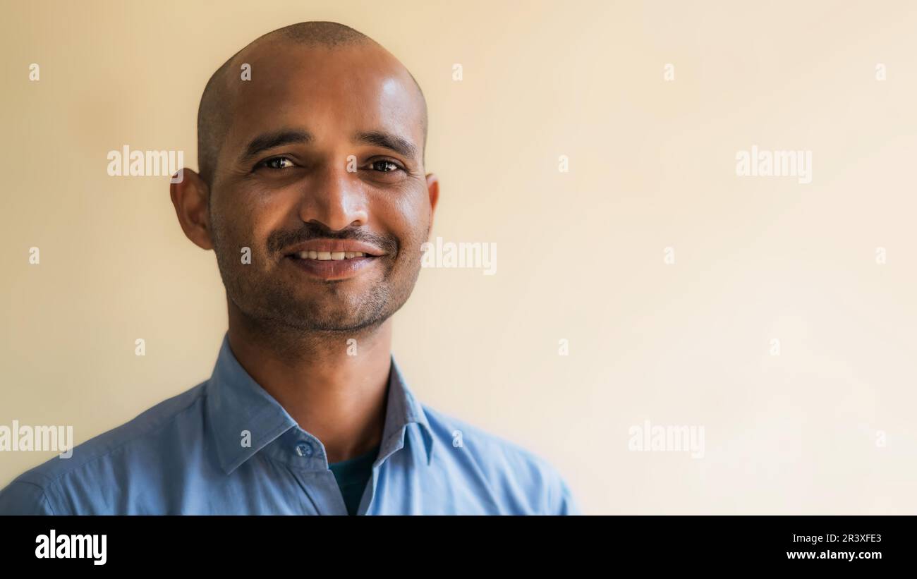 Felice uomo indiano che indossa una camicia blu e sorridente. Foto Stock