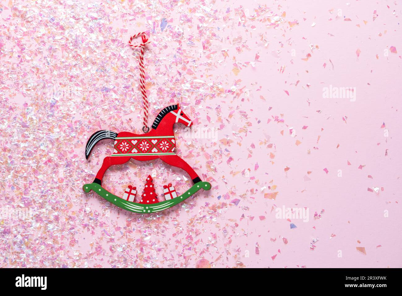 Albero di Natale giocattolo di legno di cavallo dondolo su sfondo rosa con glitter. Disposizione piatta, vista dall'alto con spazio per la copia Foto Stock