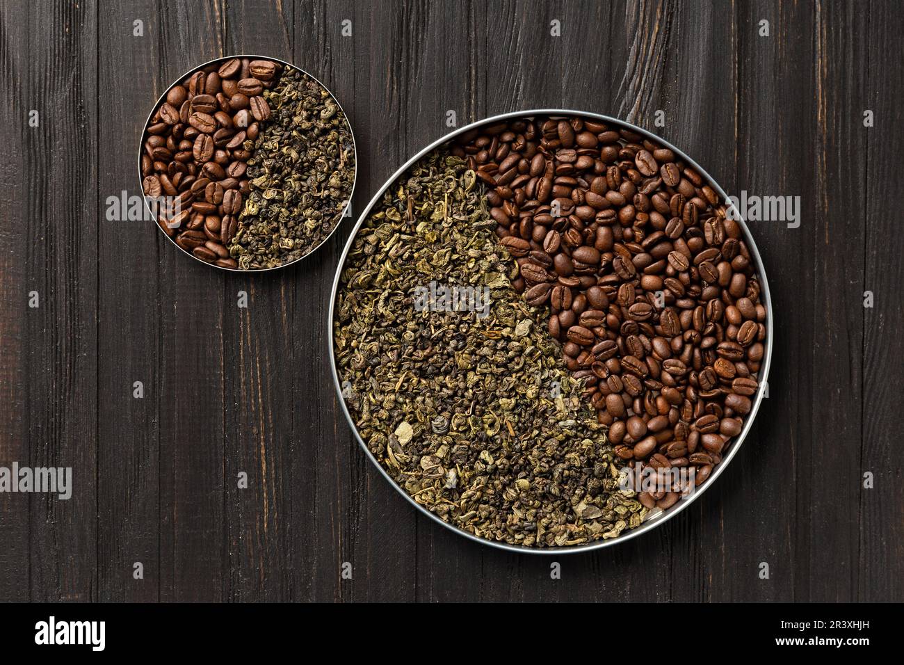 Tè verde secco e caffè in grani arrosto in due piatti rotondi di diverse dimensioni su uno sfondo di legno scuro vista dall'alto copia spazio. Foto Stock