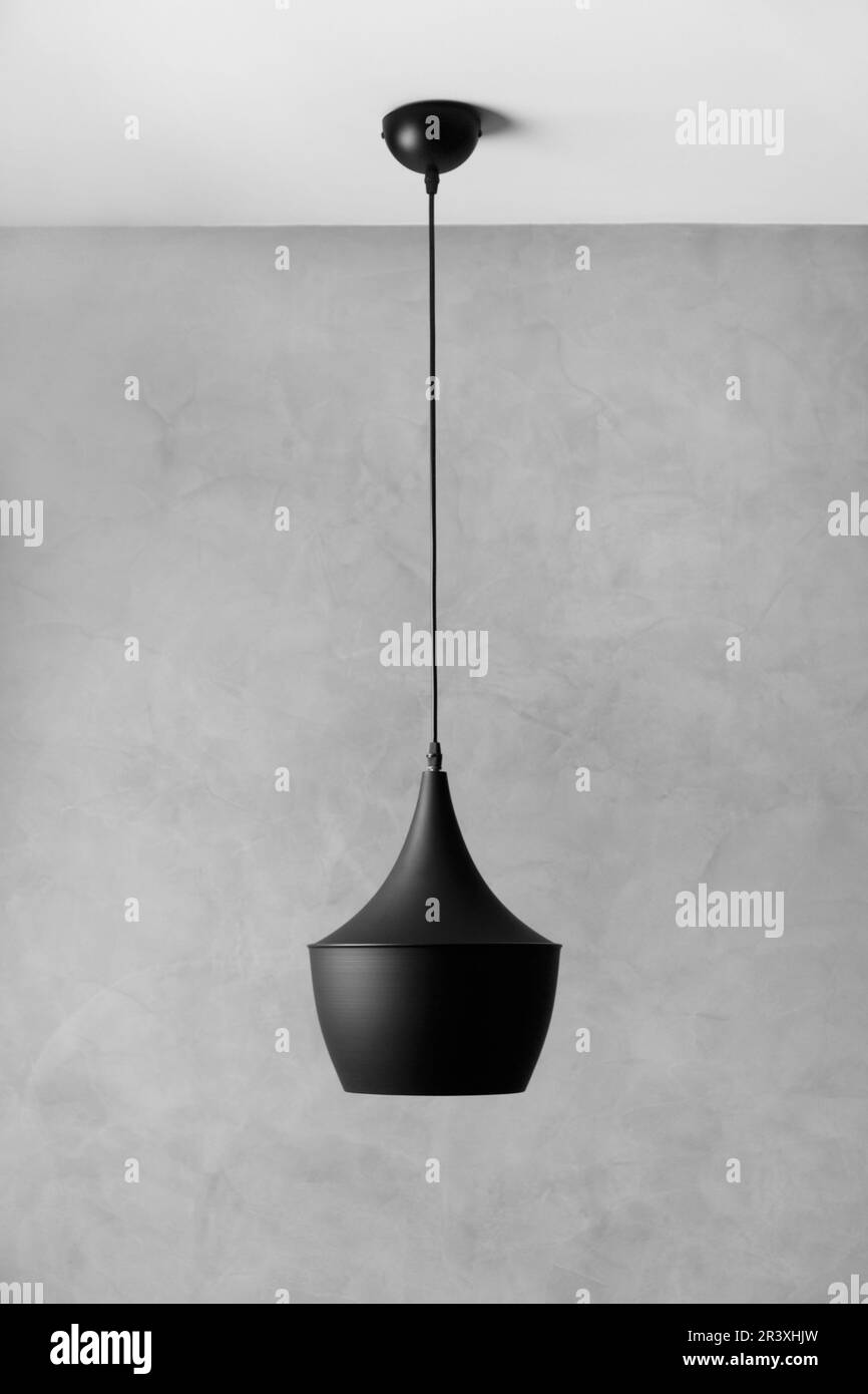 Moderno lampadario a soffitto in metallo nero in stile loft contro una parete con intonaco grigio decorativo. Lampada di design nera su sfondo grigio. Foto Stock