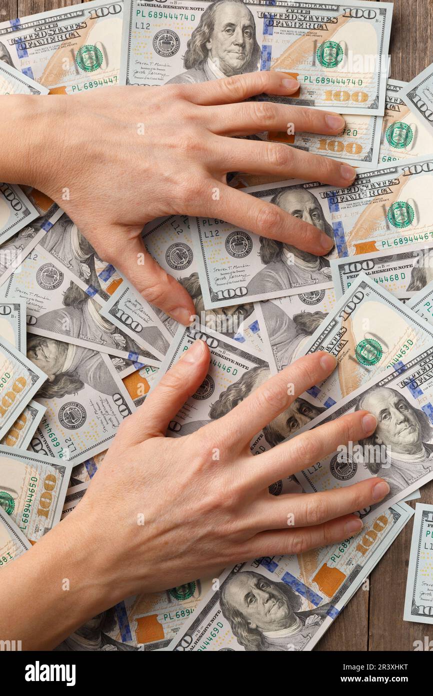 Mani avide coperte e premi banconote di 100 dollari. Il concetto di avidità, corruzione, corruzione, stinginess, affari, profitto, accumulazione. Foto Stock
