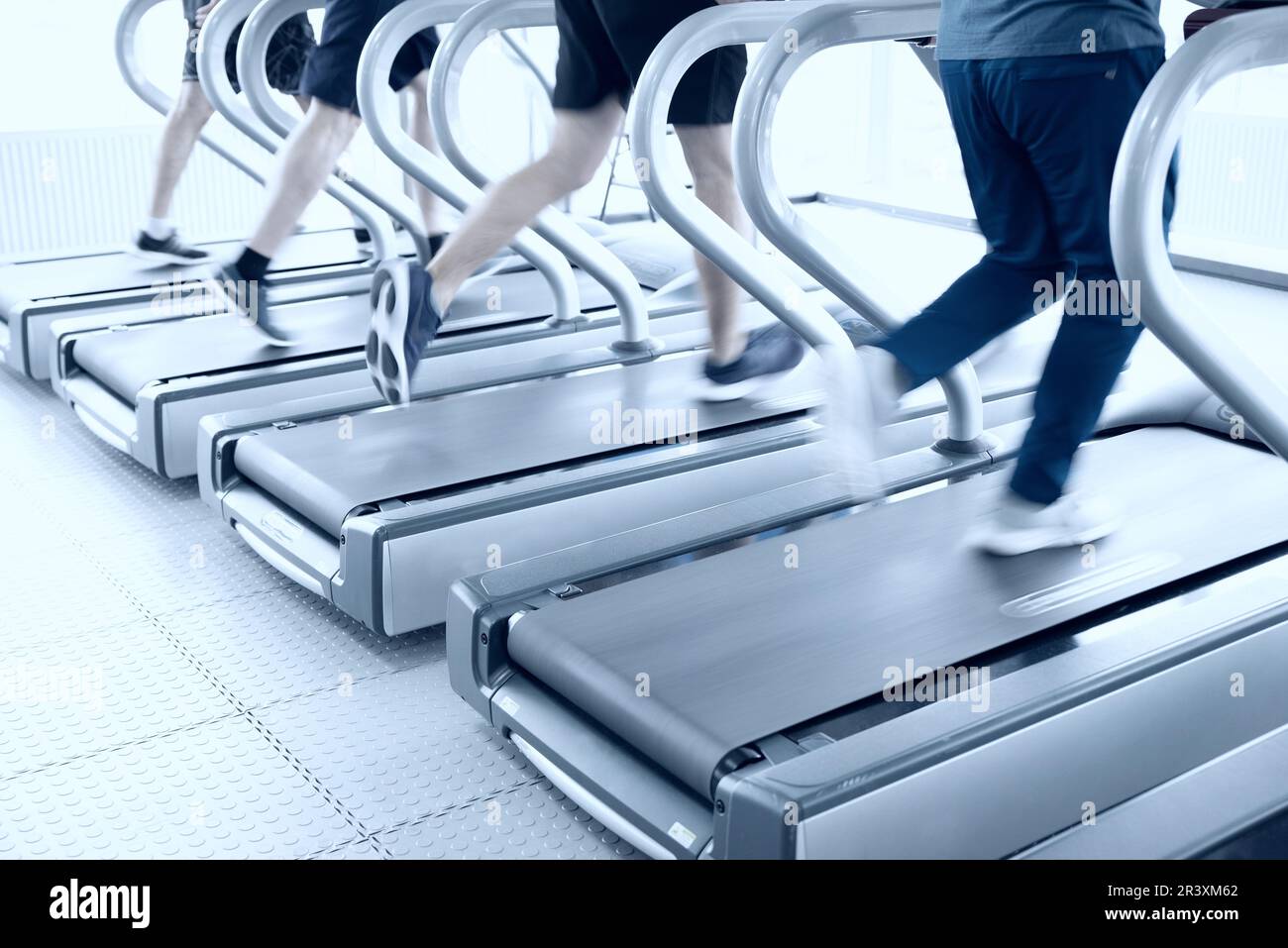 Persone che corrono su macchine, tapis roulant con sfocatura del movimento, tono blu Foto Stock