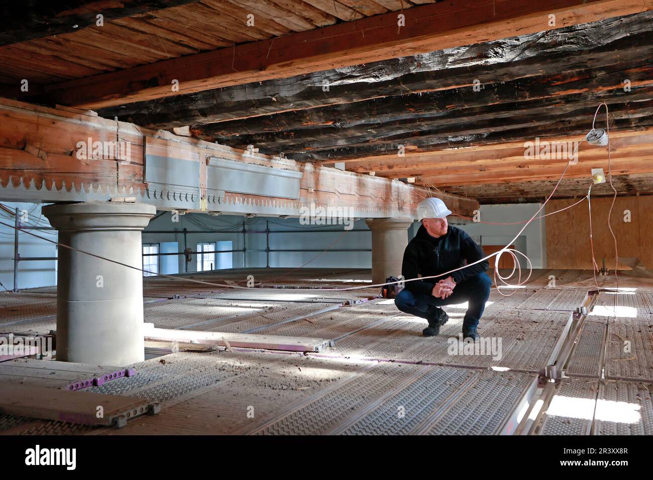 25 maggio 2023, Sassonia-Anhalt, Wernigerode: Immo Kramer, direttore dell'ufficio delle costruzioni, guarda da un controsoffitto alle travi a vista nella grande sala da ballo sbugiata del municipio di Wernigerode. Il municipio storico è attualmente in fase di ristrutturazione secondo l'ordine di conservazione. Nell'area della sala si notarono notevoli vibrazioni del pavimento. Quando il soffitto sottostante è stato aperto, è stato trovato che la costruzione esistente (spaziatura e apertura delle travi del soffitto) era troppo debole per l'uso previsto. Pertanto, è obbligatorio un rinforzo strutturale delle travi a soffitto. Il im Foto Stock