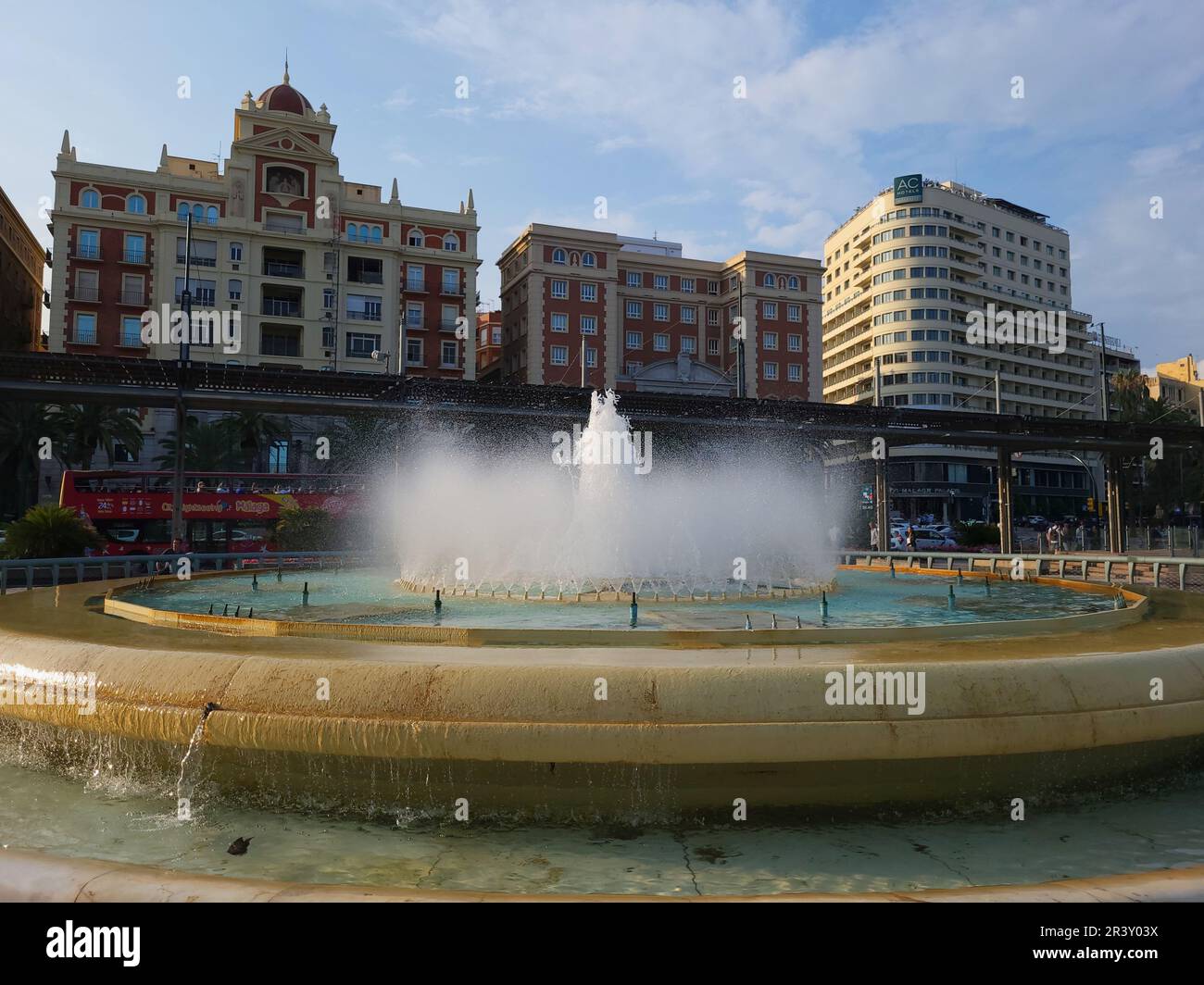Fontana a Plaza de la Marina con edifici storici e l'Hotel AC Málaga Palacio sullo sfondo. Foto Stock