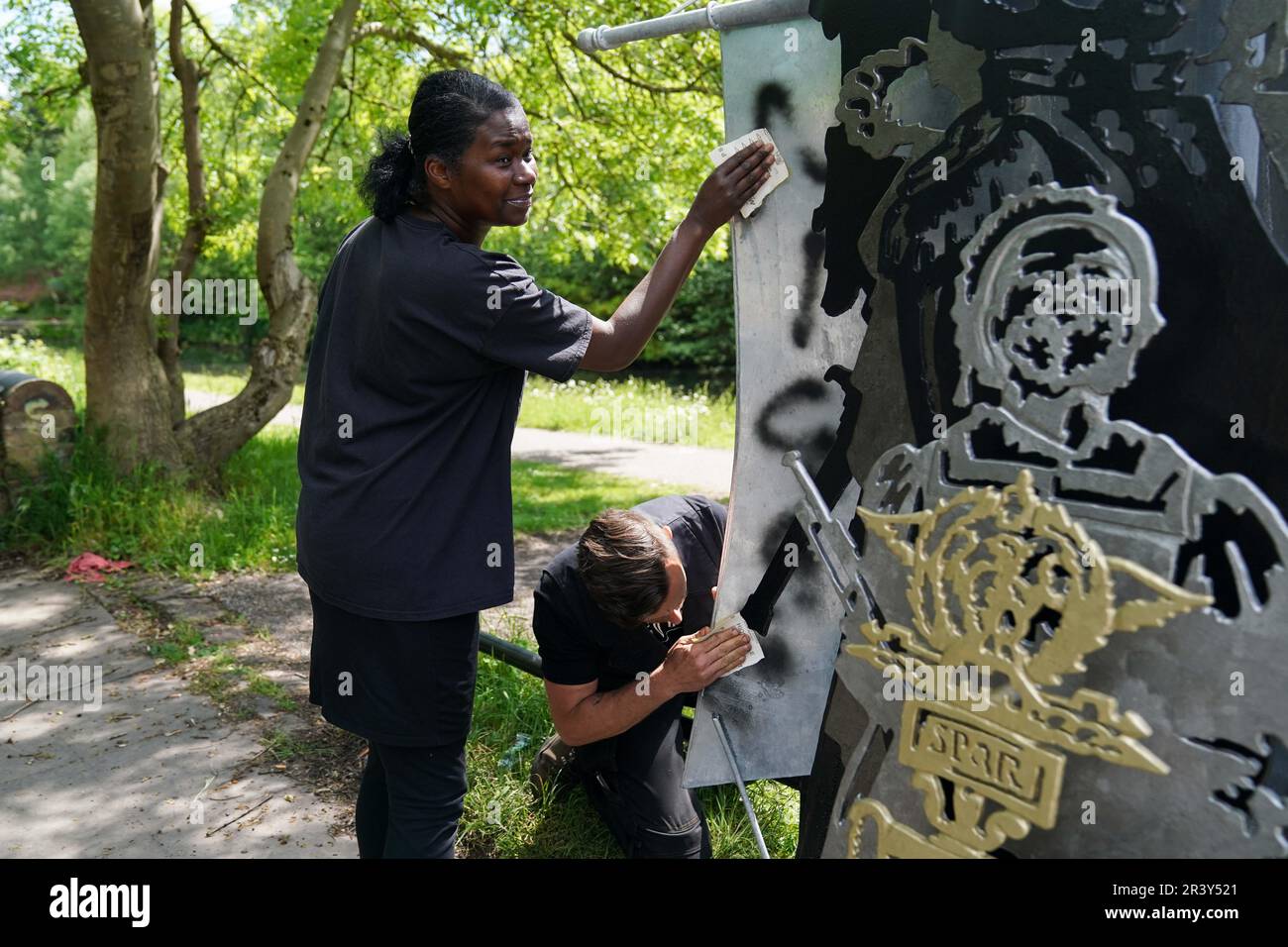 NOTA: LINGUA SULLA SCULTURA marcia Dunkley dal Black Heritage Walks Network e artista Luke Perry pulito razziale slur graffiti fuori dalla sua scultura, la storia britannica nera è la storia britannica, dal Soho Loop Canal a Winson Green, Birmingham dopo che è stato vandalizzato. Data immagine: Giovedì 25 maggio 2023. Foto Stock