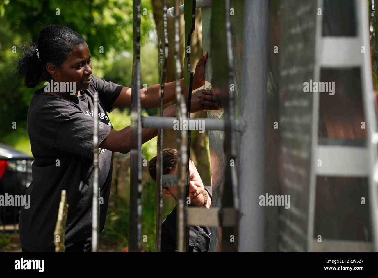 NOTA: LINGUA SULLA SCULTURA marcia Dunkley dal Black Heritage Walks Network e artista Luke Perry pulito razziale slur graffiti fuori dalla sua scultura, la storia britannica nera è la storia britannica, dal Soho Loop Canal a Winson Green, Birmingham dopo che è stato vandalizzato. Data immagine: Giovedì 25 maggio 2023. Foto Stock