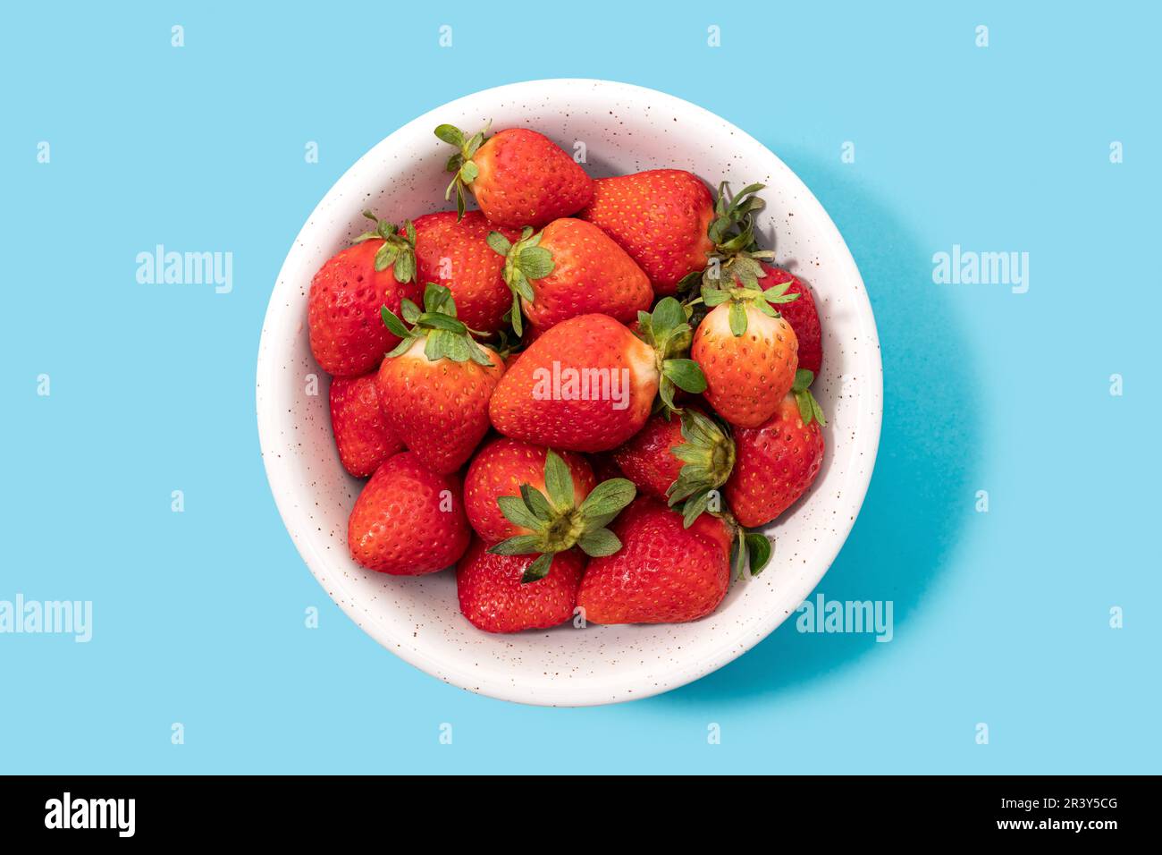 Fragole fresche in ciotola isolata su fondo blu. Vista dall'alto Foto Stock