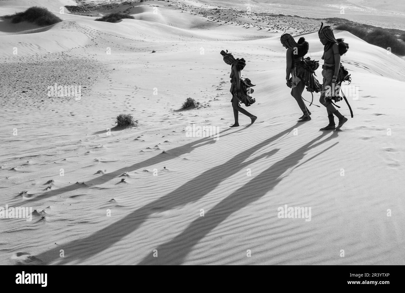 Tre donne della tribù Himba in abiti tradizionali camminano nel deserto. Foto Stock