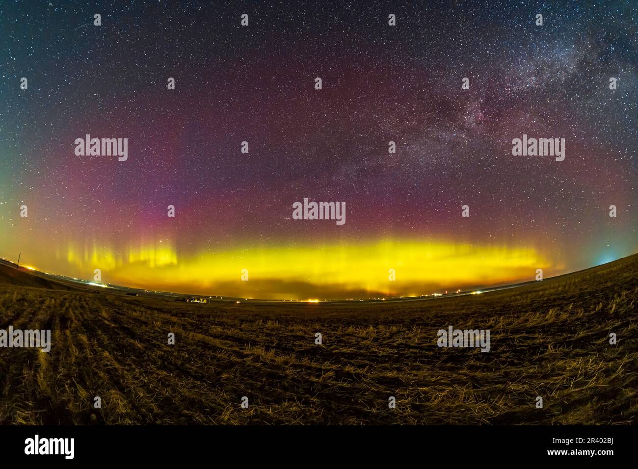 Arco di verde e rosso aurora attraverso l'orizzonte settentrionale in Alberta, Canada. Foto Stock