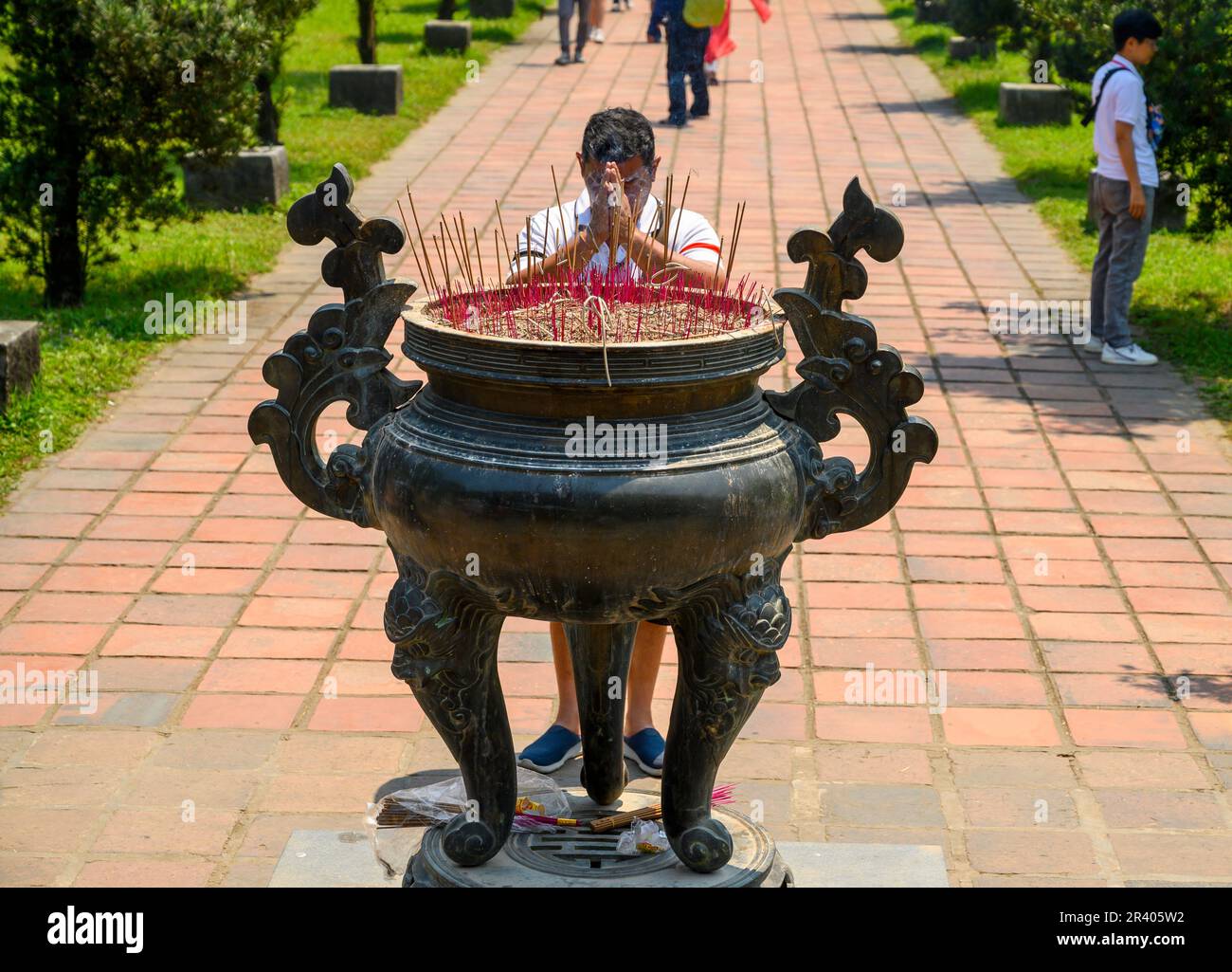 Un buddista prega con un bruciatore di incenso alla Pagoda Thien Mu di Hue, in Vietnam. Foto Stock
