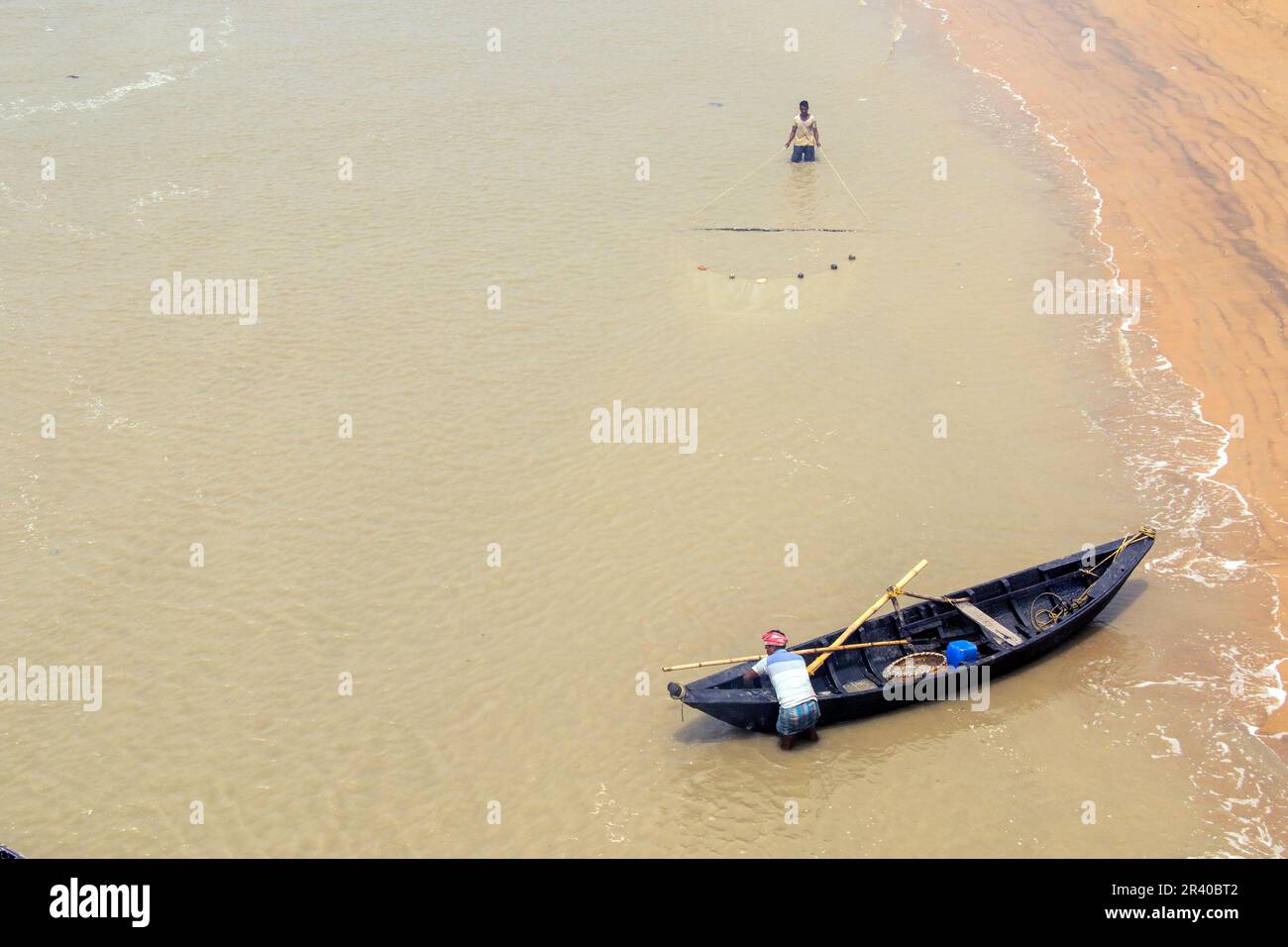 Pescatori e donne stanno lavorando per catturare gamberi nel fiume nella calda mattina di sole. Foto Stock