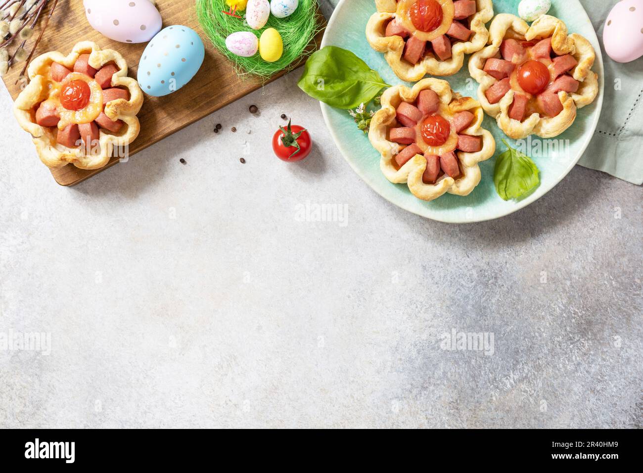 Ideale per colazione o pranzo di Pasqua. Mini pizza. Pizza in pasta sfoglia con formaggio e pomodori sul tavolo festivo. Vista da ab Foto Stock