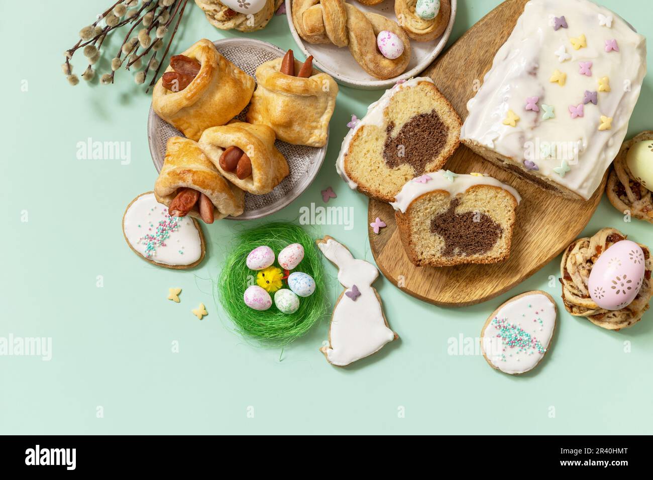 Cena festiva, brunch di Pasqua. Felice Pasqua vacanza cibo cottura pasta sfoglia e cupcake con coniglietto di Pasqua su sfondo verde pastello Foto Stock