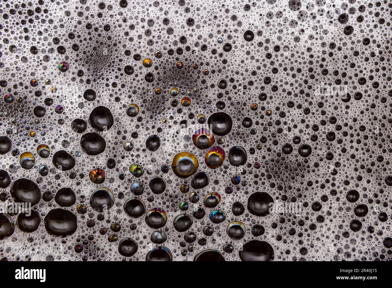 Goiânia, Goias, Brasile – 22 maggio 2023: Dettaglio della struttura della schiuma con bolle che riflettono vari colori, su una superficie nera. Foto Stock