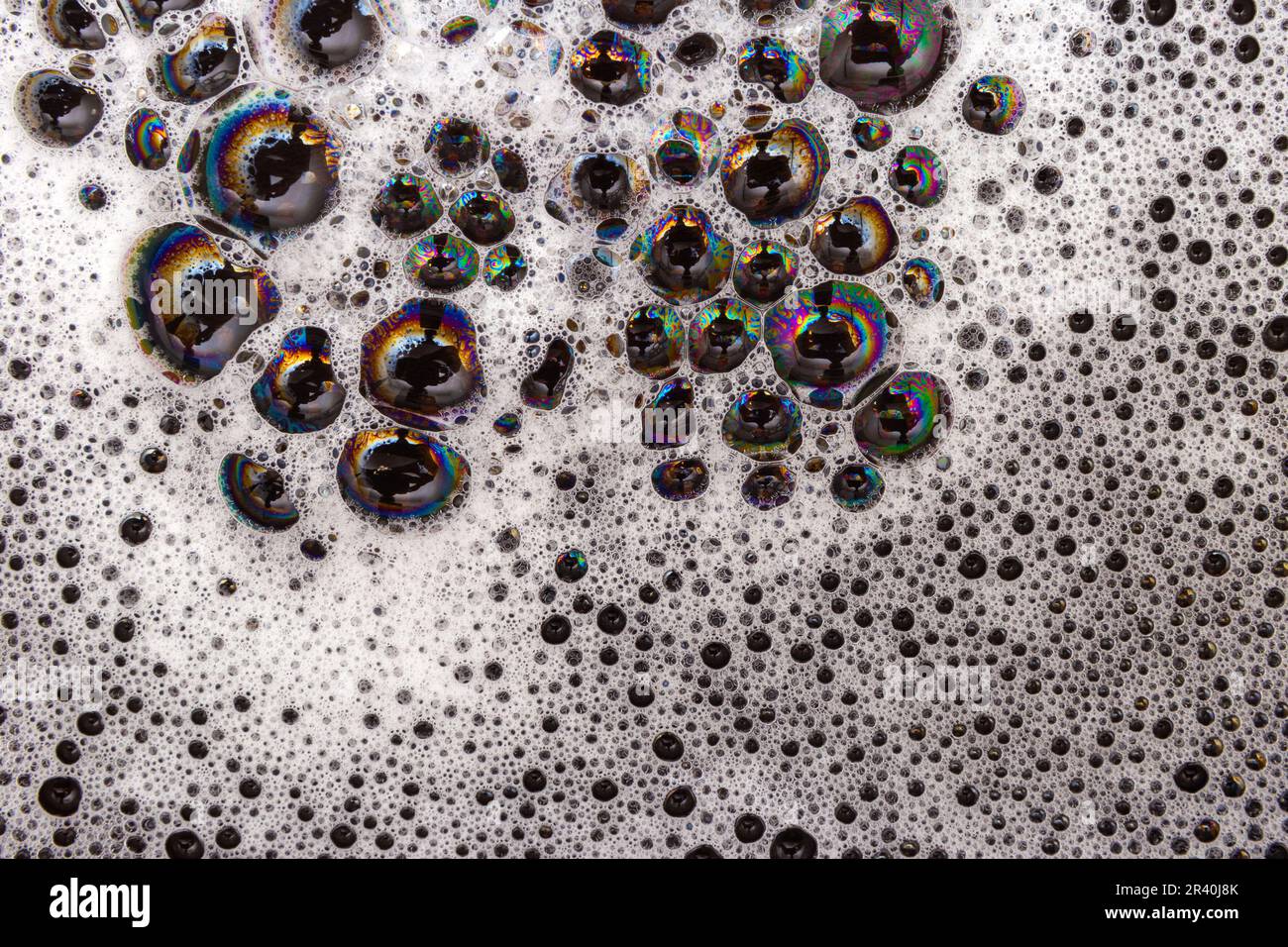 Goiânia, Goias, Brasile – 22 maggio 2023: Dettaglio della struttura della schiuma con bolle che riflettono vari colori, su una superficie nera. Foto Stock