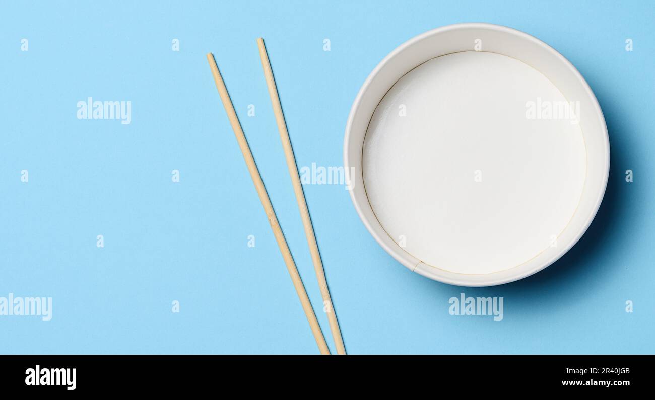 Aprire la ciotola vuota con un paio di bastoncini di legno su sfondo blu, vista dall'alto Foto Stock
