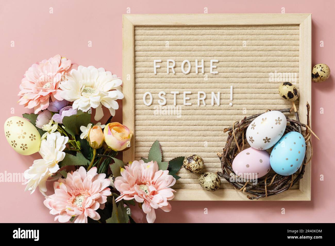 Frohe Ostn - buona Pasqua in tedesco saluto, uova di Pasqua e fiori primaverili su sfondo rosa pastello, stile minimalismo com Foto Stock