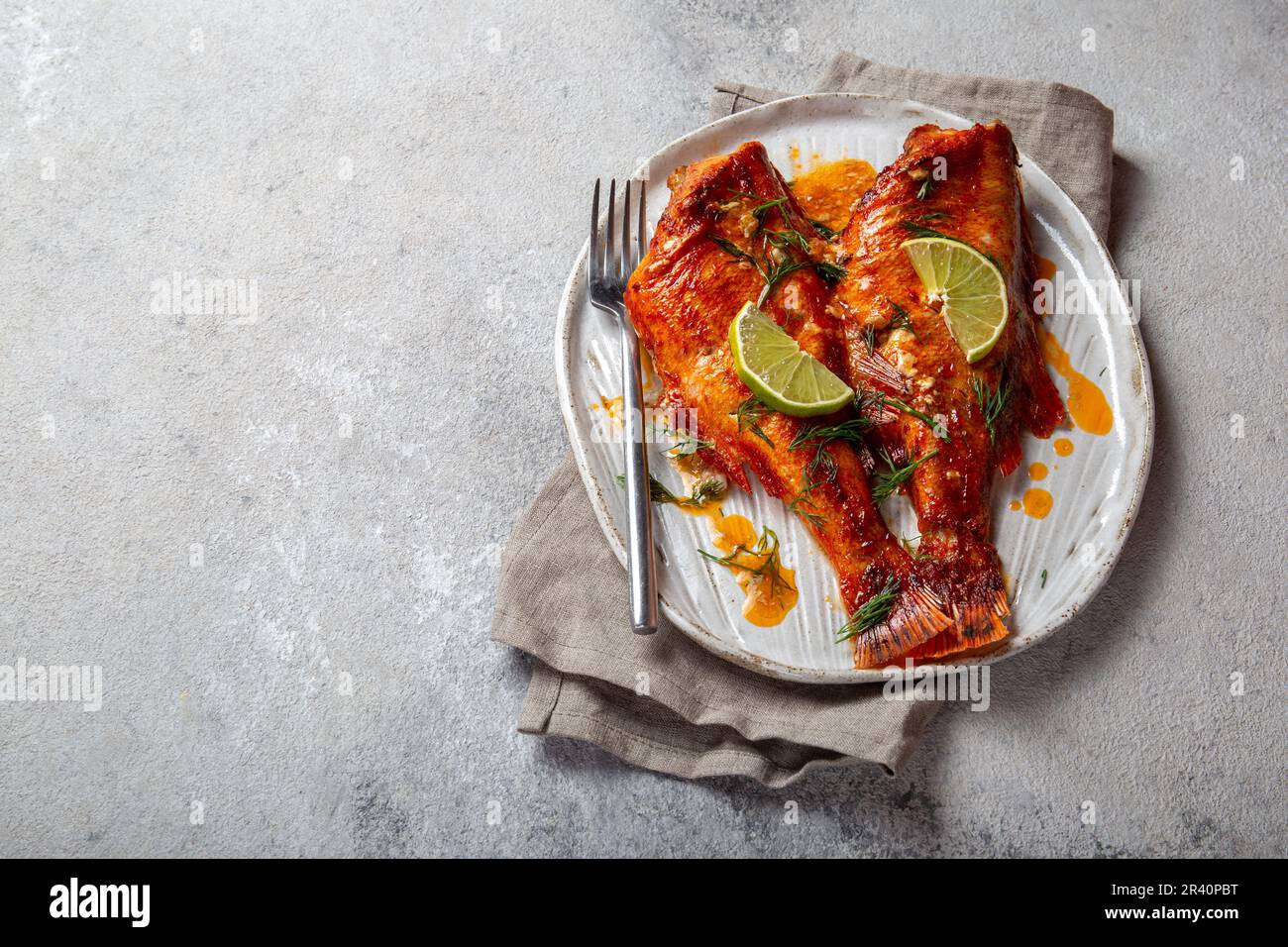 Cotta Red sea bass in kraft piastra bianca, concreto sfondo. Foto Stock