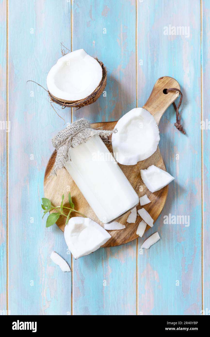 Latte alternativo vegano non caseario, contenuto sanitario. Latte di cocco biologico in una bottiglia su un tavolo rustico. Vista dall'alto. Foto Stock