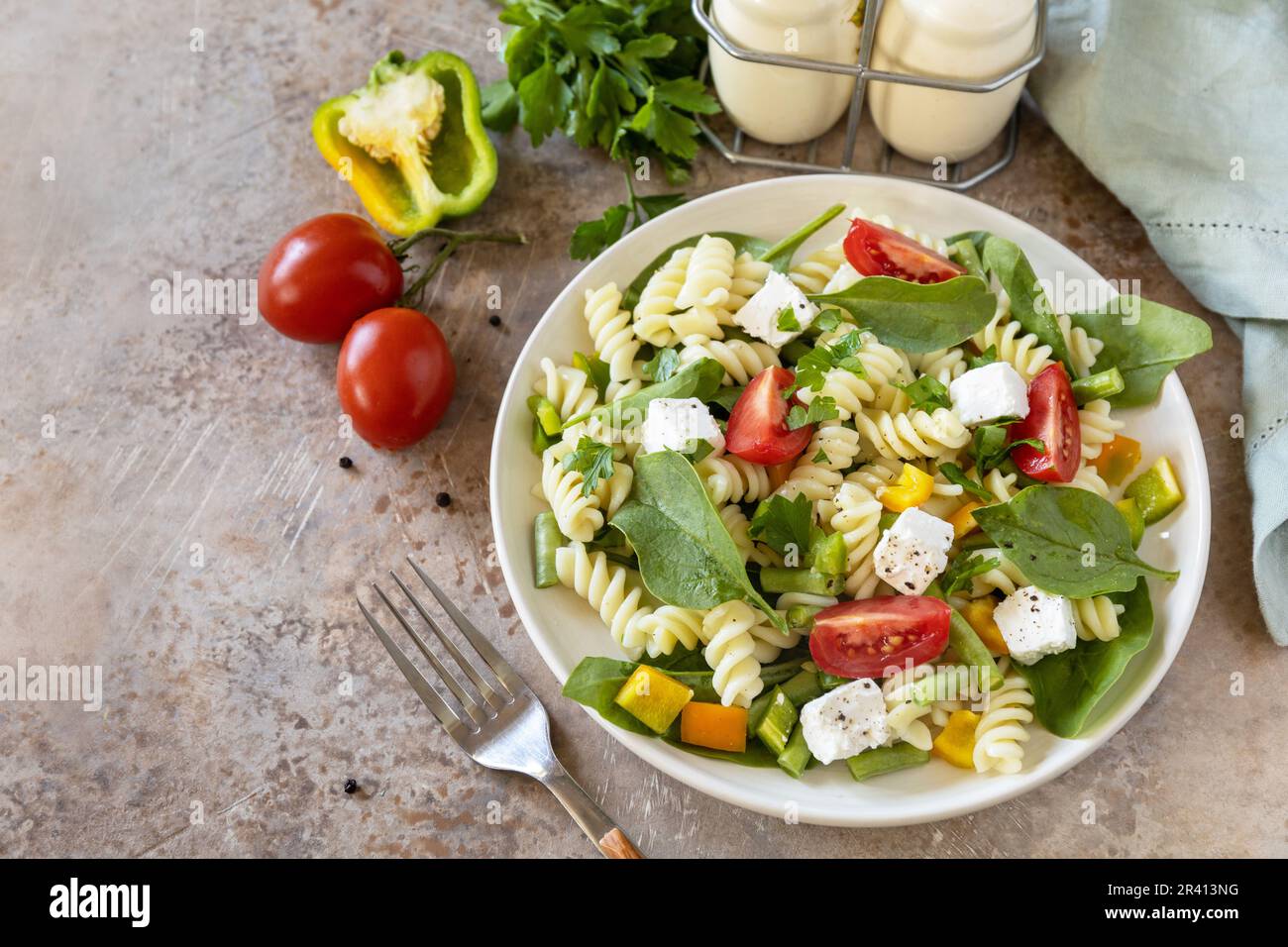 Cibo italiano - insalata con pasta senza glutine, spinaci, pomodori, fagioli e formaggio feta su un tavolo di pietra. Cibo sano, vegetariano Foto Stock