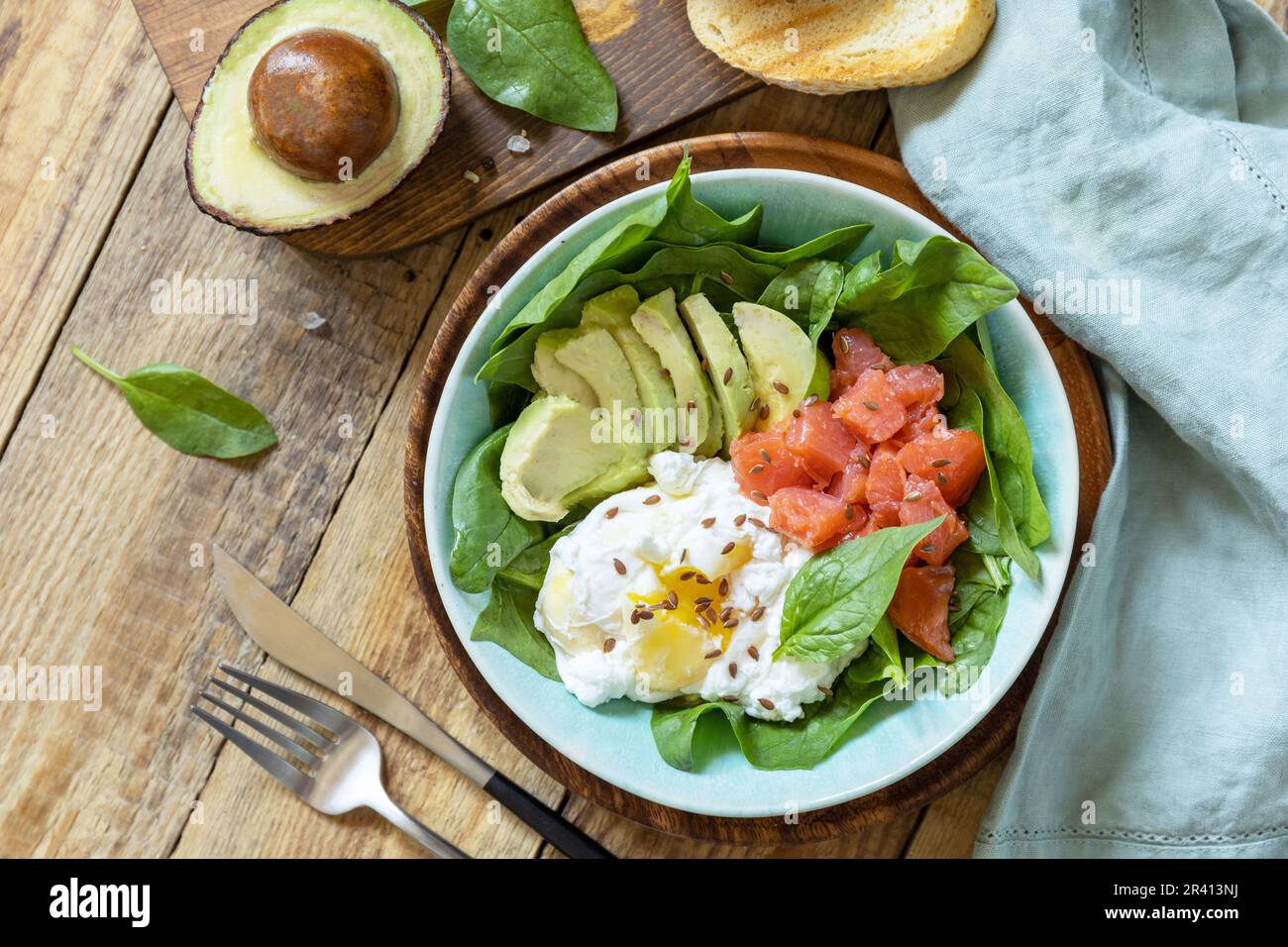 Deliziosa colazione o pranzo con pesce salmone salato, avocado, uova bollite e spinaci su un tavolo rustico. Chetogenico, cheto o. Foto Stock