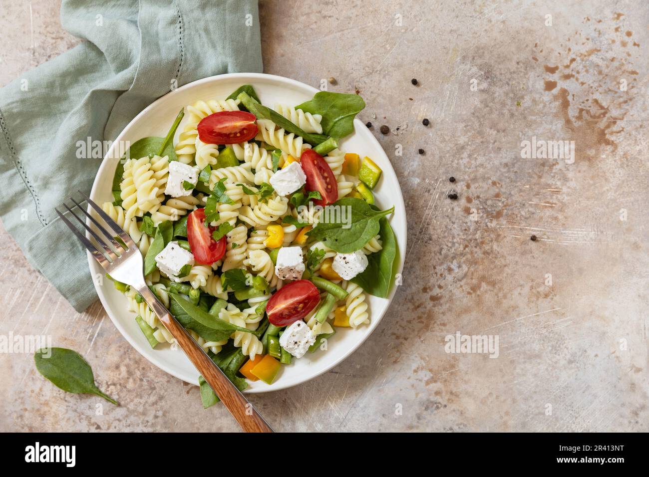 Cibo italiano - insalata con pasta senza glutine, spinaci, pomodori, fagioli e formaggio feta su un tavolo di pietra. Cibo sano, vegetariano Foto Stock