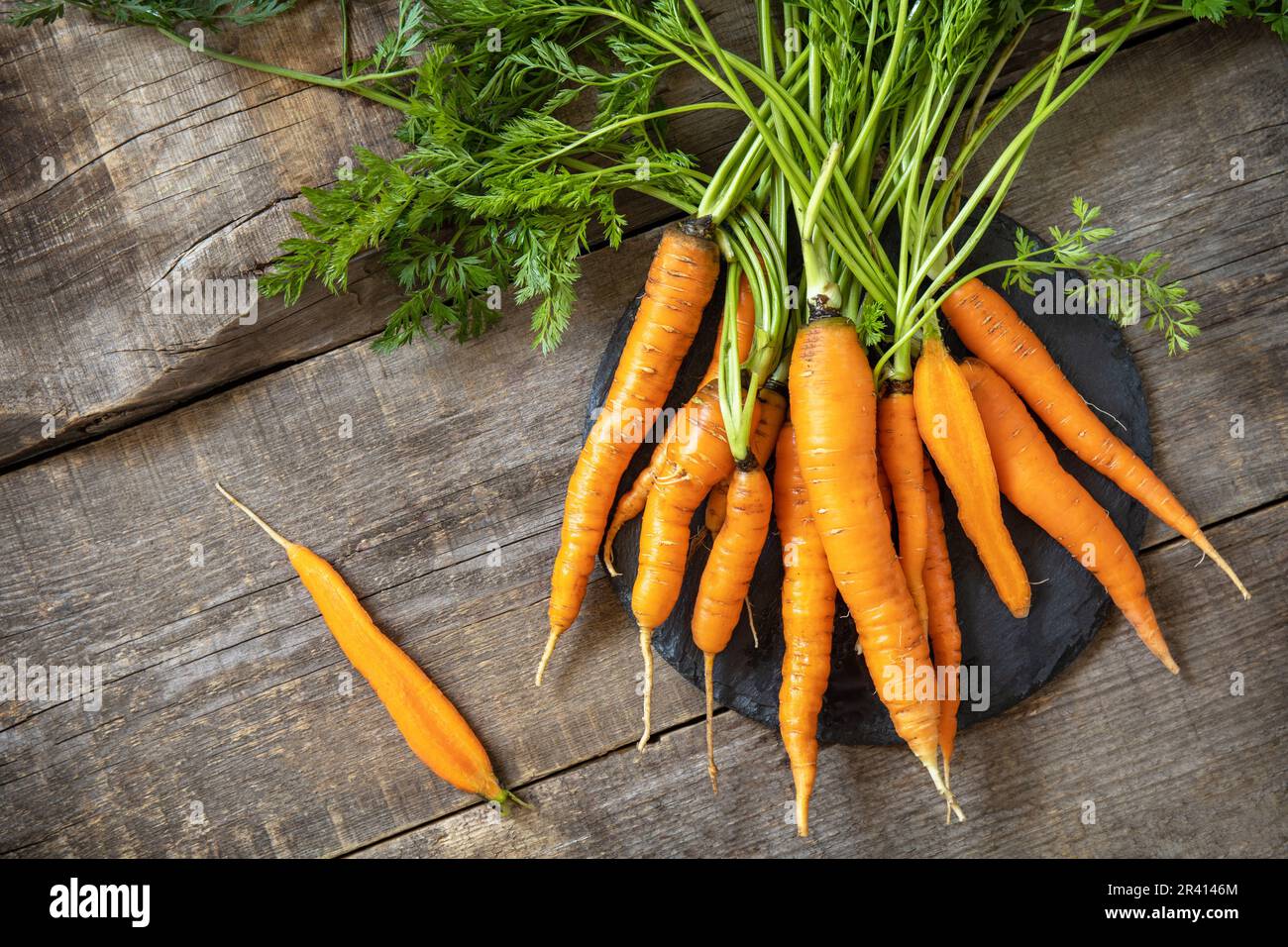 Carote sane e succose mature su un tavolo da cucina in legno. Il concetto di nutrizione biologica e di raccolta di verdure autunnali. Top vie Foto Stock