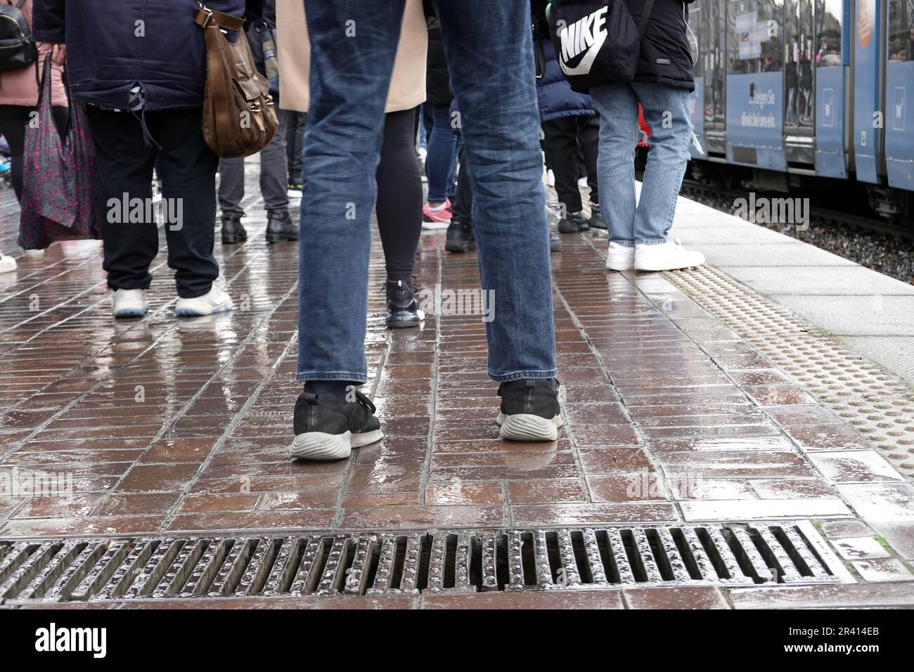 Numerose persone in attesa di tram sotto la pioggia Foto Stock